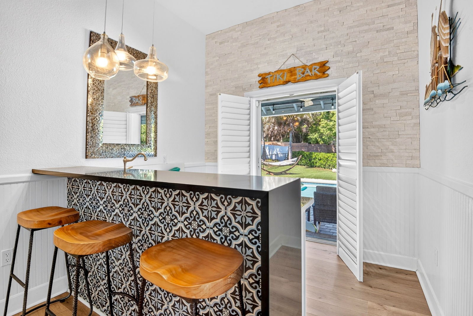 Tiki bar with hand-painted tile and a view to the pool