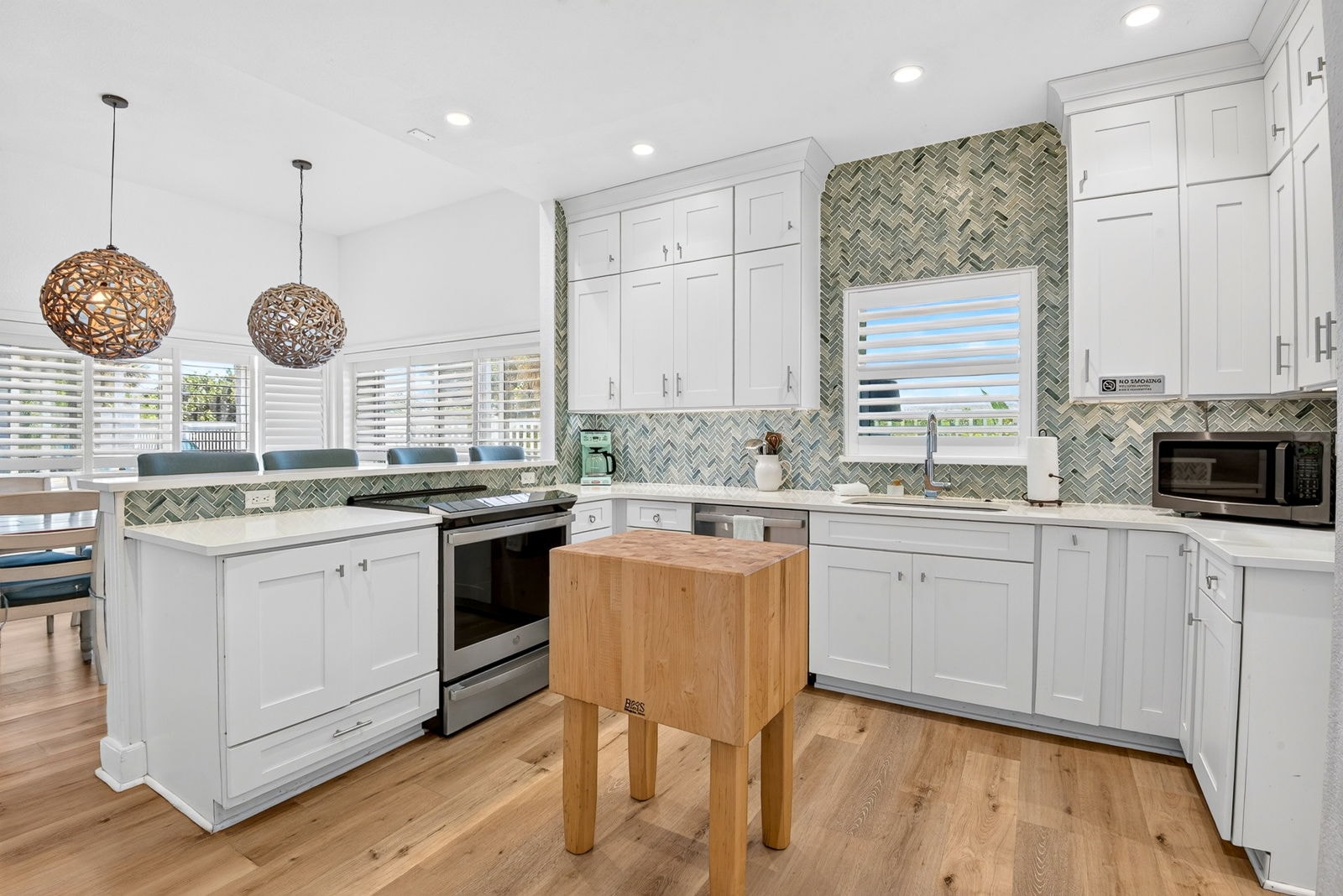Bright kitchen with white cabinetry and coastal tile backsplash